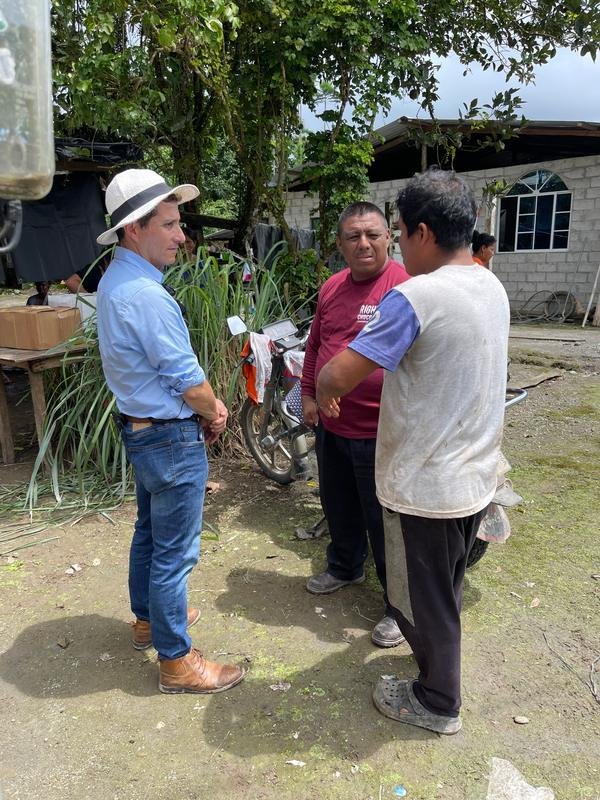 Tres hombres conversando frente a una casa de finca
